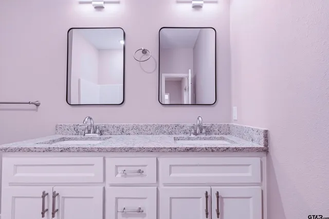a bathroom with double vanity sinks and two mirror