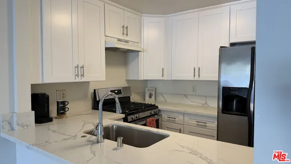 a kitchen with stainless steel appliances kitchen island granite countertop a refrigerator and a stove top oven