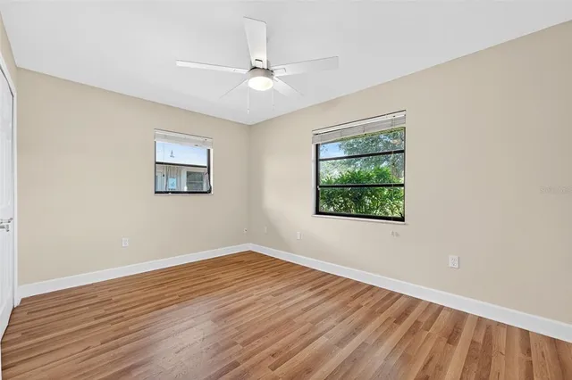 a view of an empty room with wooden floor and a window