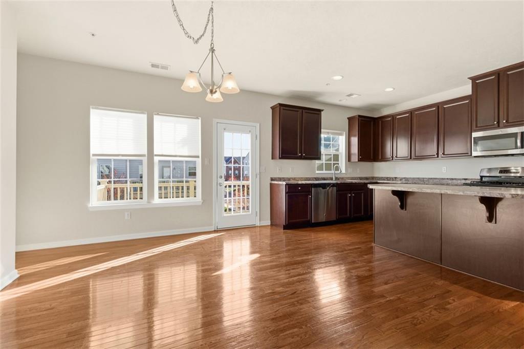 3001 Pointe View Drive Mars, PA 16046 - Photo 20 of 48 a open kitchen with granite countertop a stove top oven a sink dishwasher a dining table and chairs with wooden floor