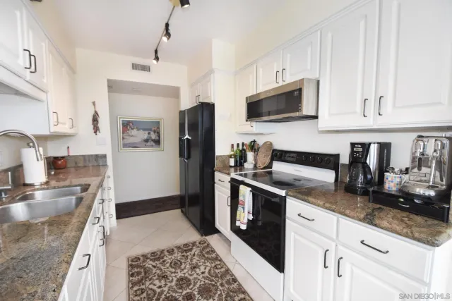 a kitchen with granite countertop a sink stove and refrigerator