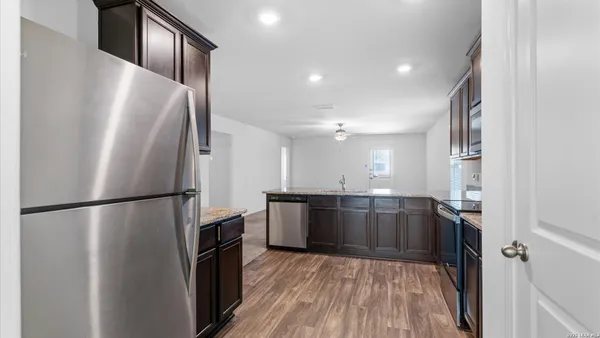 a kitchen with stainless steel appliances a refrigerator a sink and wooden floor