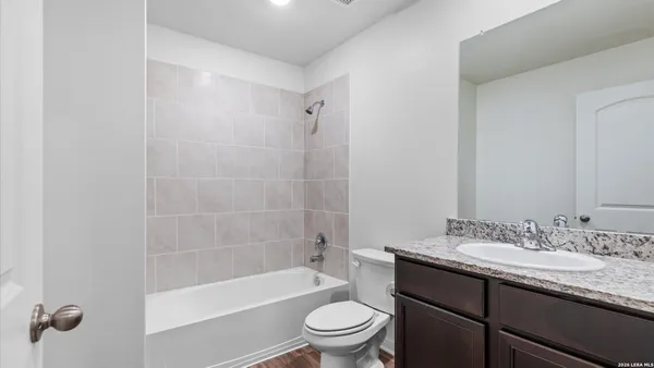 a bathroom with a granite countertop sink a toilet and shower