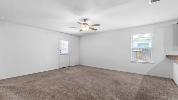 an empty room with windows and chandelier fan
