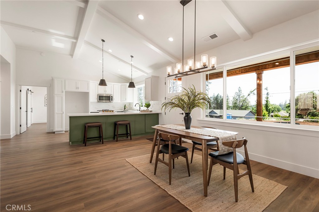 a dining hall with stainless steel appliances kitchen island granite countertop a table chairs and a chandelier