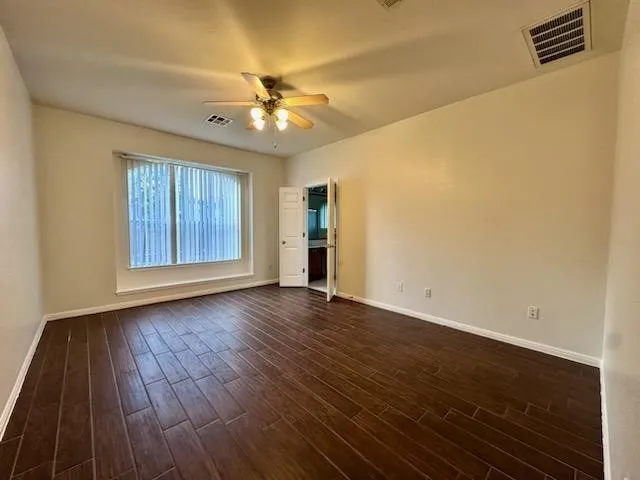 an empty room with wooden floor chandelier fan and windows