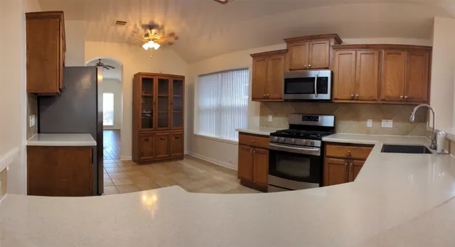 a kitchen with stainless steel appliances granite countertop a refrigerator a stove top oven a sink and dishwasher