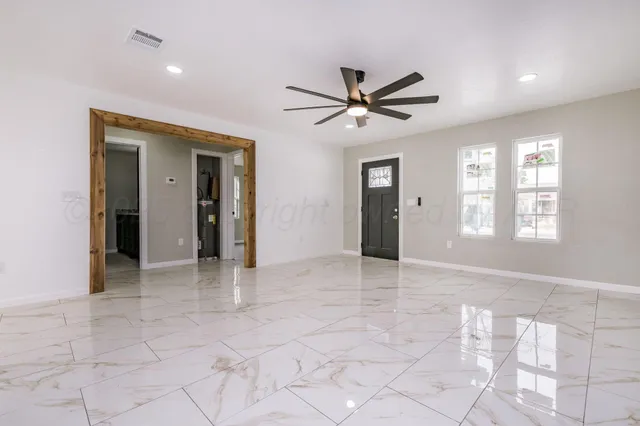 a view of an empty room with window and chandelier fan