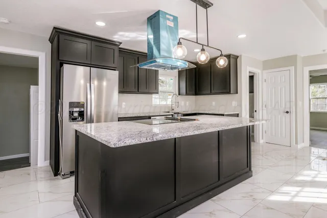 a kitchen with stainless steel appliances granite countertop a sink and a refrigerator