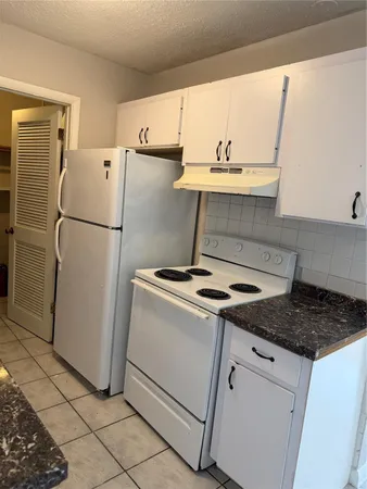 a white refrigerator freezer and a stove sitting inside of a kitchen