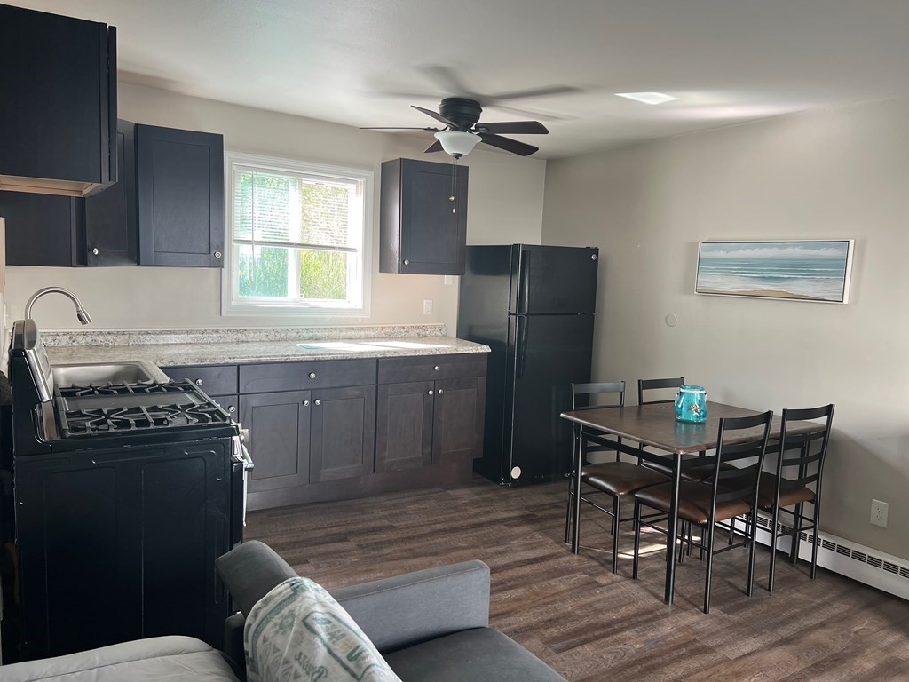 933 Ocean Boulevard, Unit 27 Hampton, NH 03842 - Photo 4 of 9 a kitchen with stainless steel appliances a table chairs and a refrigerator