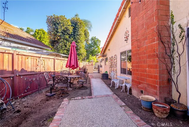 a view of a patio with table and chairs potted plants and large tree