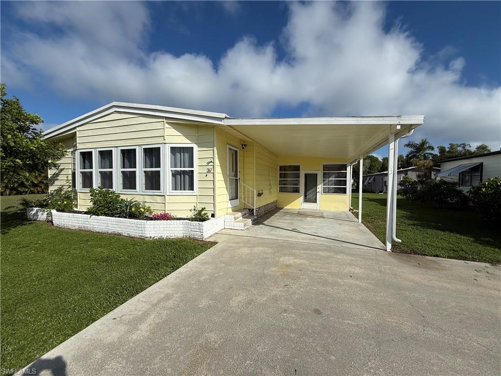 Manufactured / mobile home featuring a front lawn, driveway, an attached carport, and a patio
