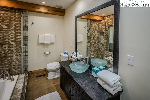 a bathroom with a granite countertop toilet a mirror and shower curtain