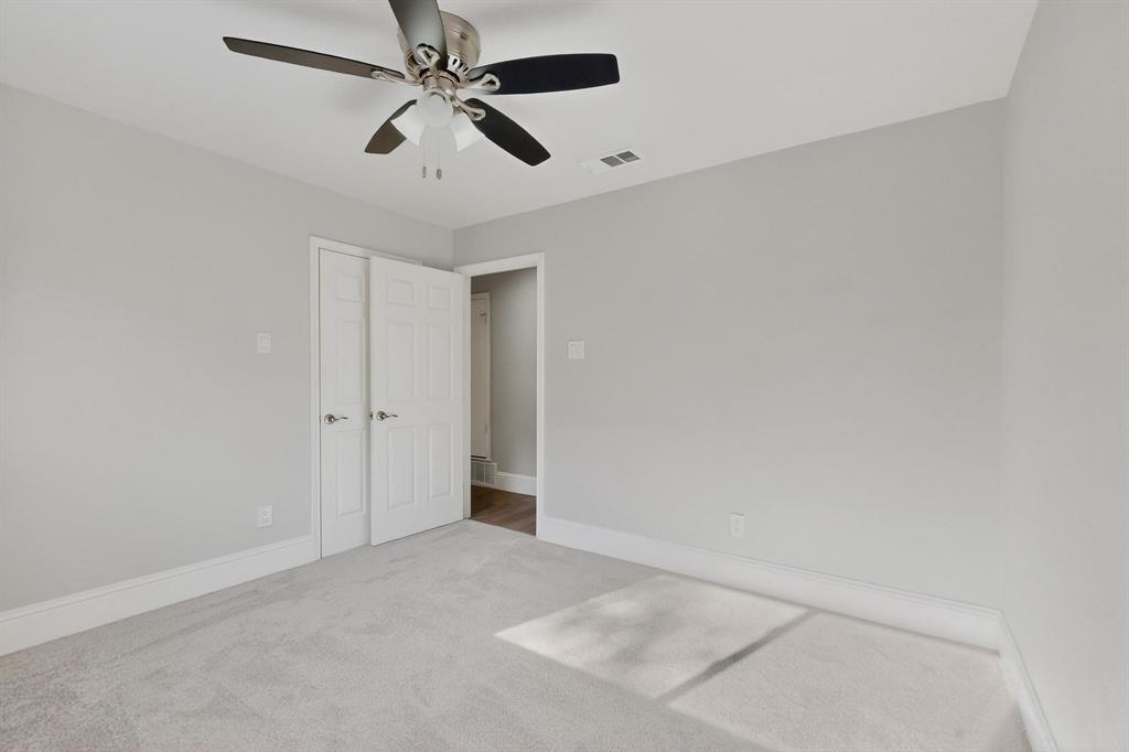 7625 Querida Lane Dallas, TX 75248 - Photo 18 of 32 an empty room with a ceiling fan and carpet