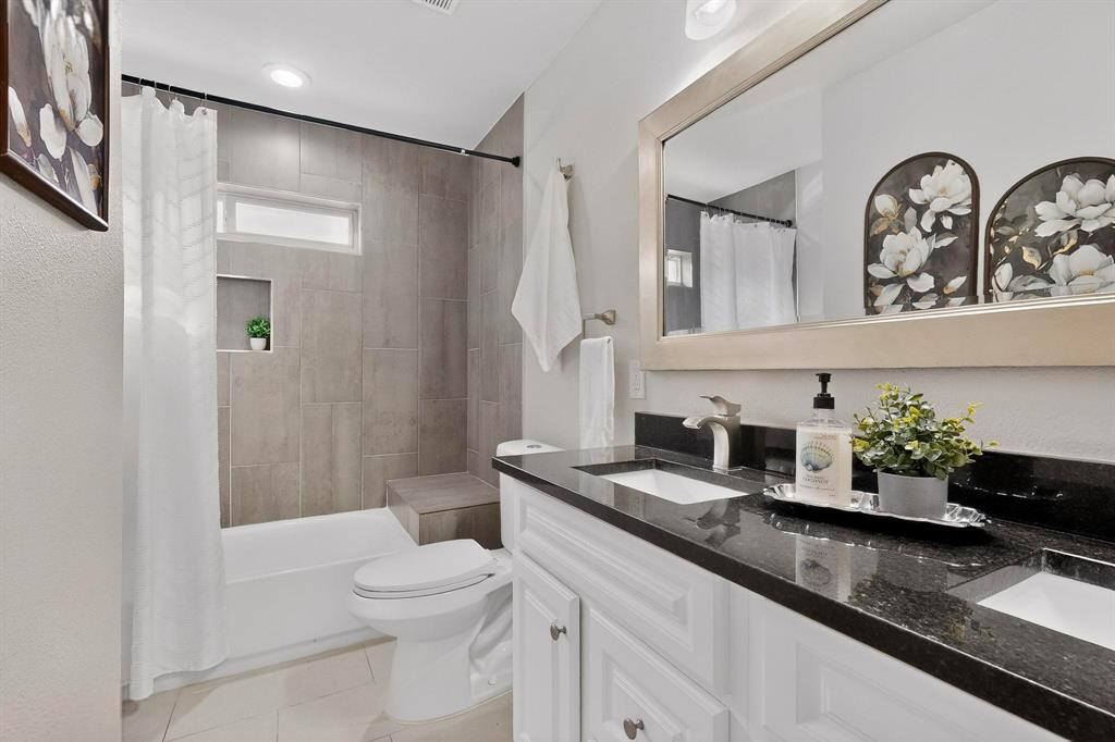 7625 Querida Lane Dallas, TX 75248 - Photo 21 of 32 a bathroom with a granite countertop toilet sink and mirror