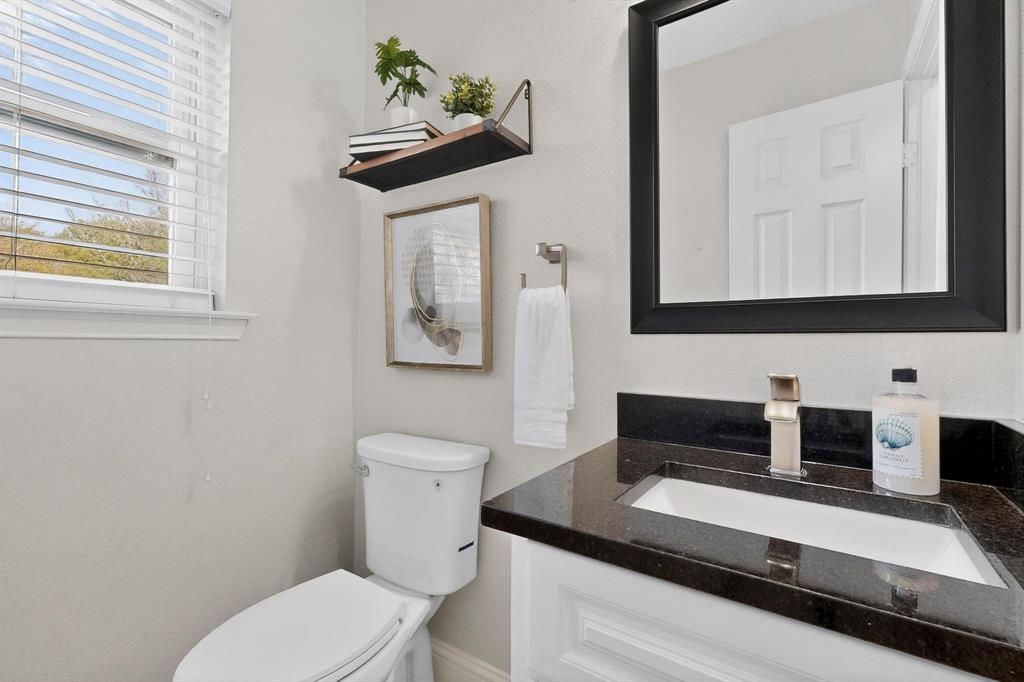 7625 Querida Lane Dallas, TX 75248 - Photo 22 of 32 a bathroom with a toilet a sink and a mirror