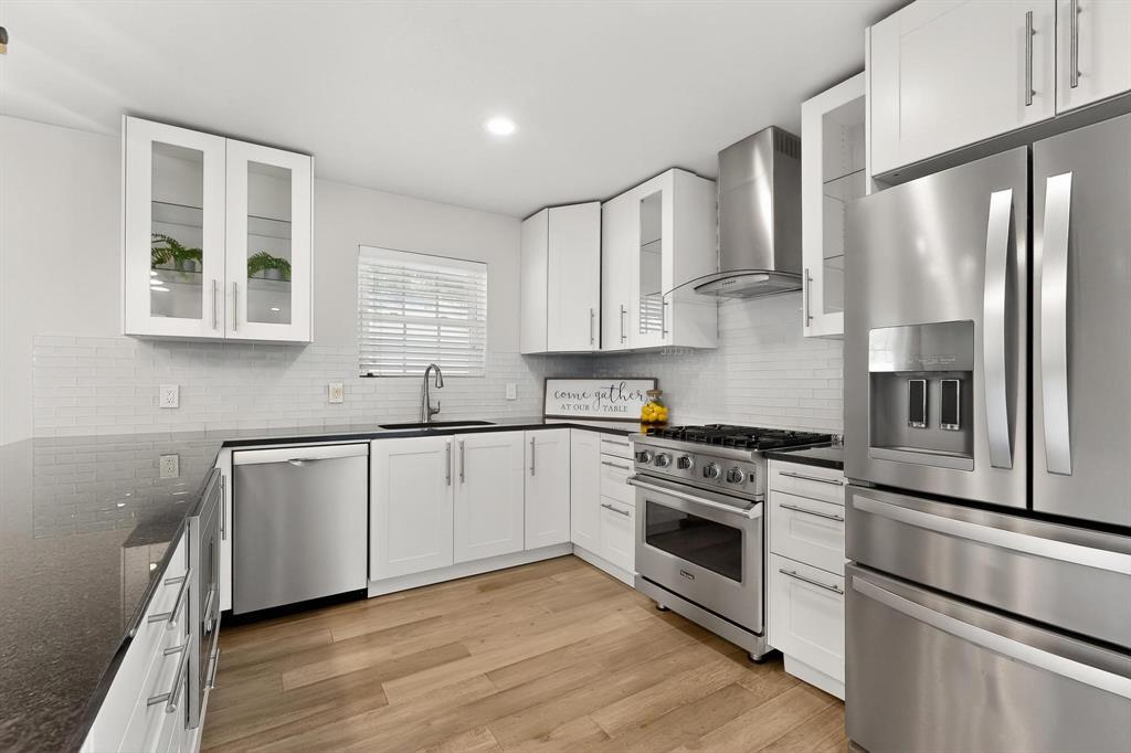 7625 Querida Lane Dallas, TX 75248 - Photo 6 of 32 a kitchen with stainless steel appliances white cabinets and wooden floor