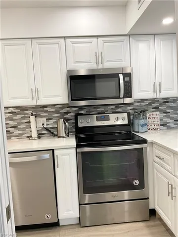 a kitchen with white cabinets and white appliances