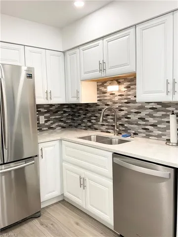 a kitchen with stainless steel appliances kitchen island granite countertop a table chairs sink and cabinets