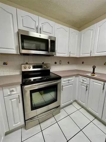 a kitchen with white cabinets and stainless steel appliances