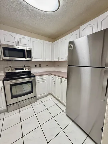 a kitchen with a refrigerator a stove top oven a sink and cabinets