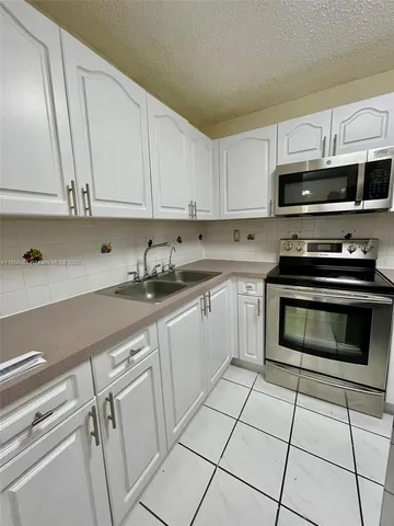 a kitchen with cabinets stainless steel appliances and a sink