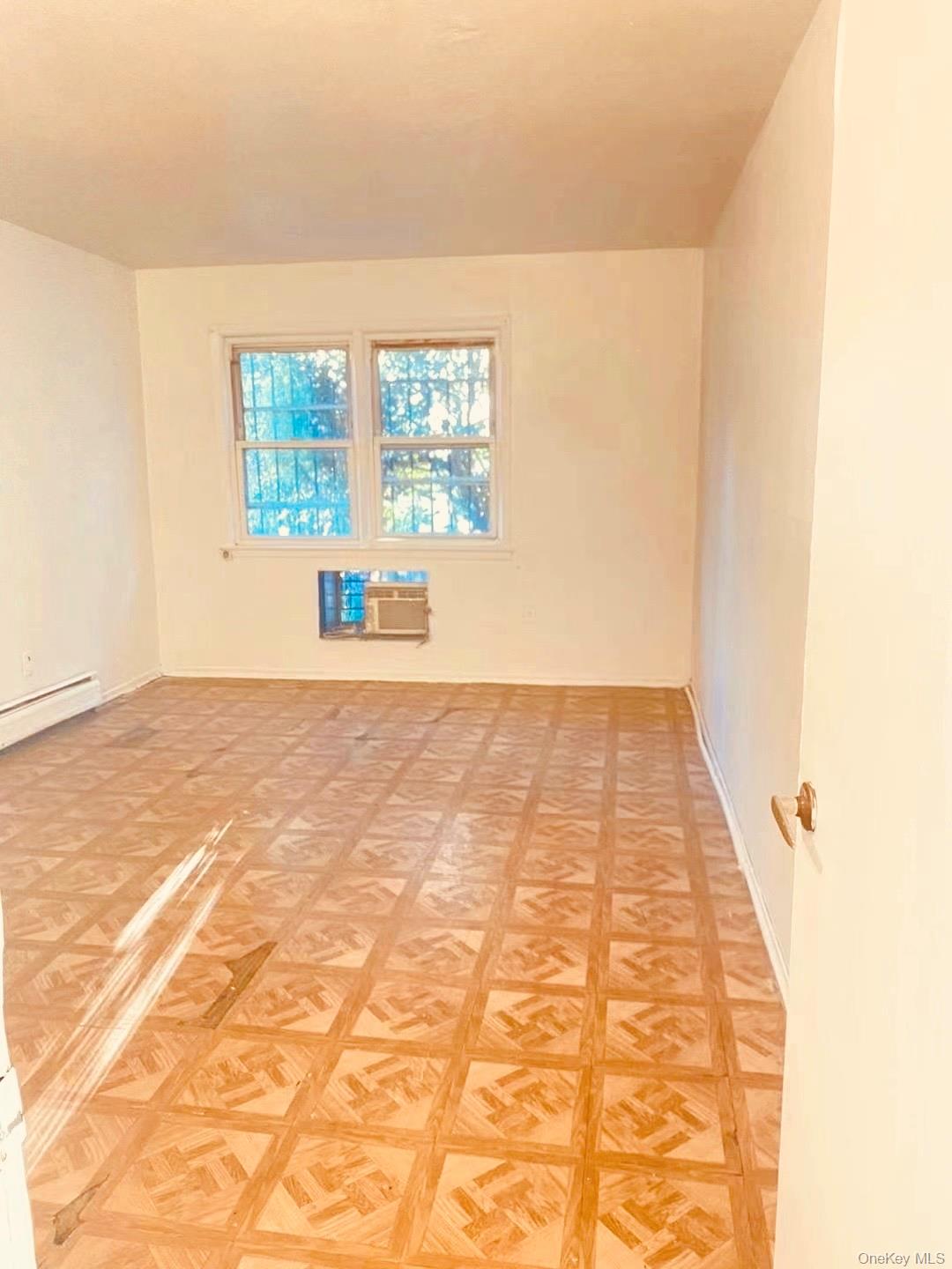 41-08 111th Street Queens, NY 11368 - Photo 6 of 9 an empty room with wooden floor and windows