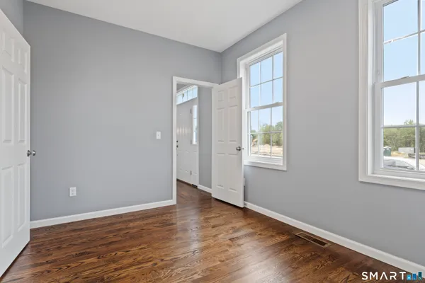 a view of an empty room with wooden floor and a window