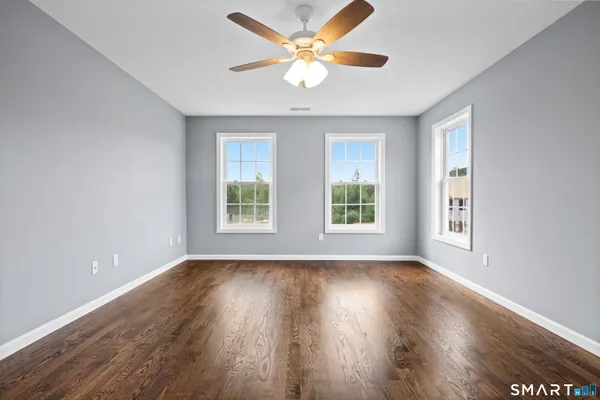 a view of an empty room with wooden floor and a window