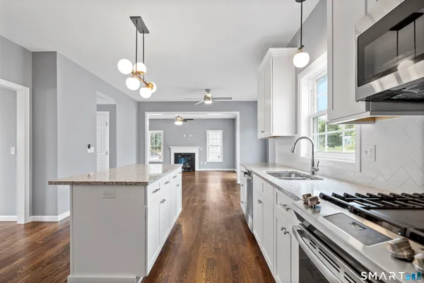 a large kitchen with stainless steel appliances granite countertop a stove and a sink with living room