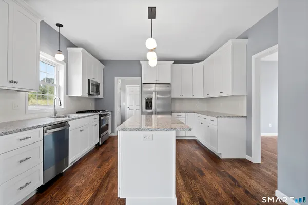 a kitchen with granite countertop a stove a sink a window and dining table