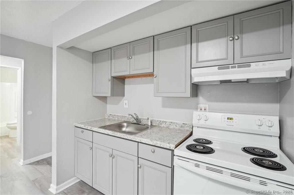 1150 Ogden St Extension, Unit 208 Bridgeport, CT 06610 - Photo 3 of 7 a kitchen with white cabinets and appliances