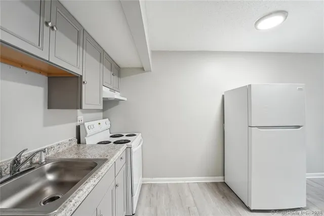 a kitchen with a sink a refrigerator and cabinets