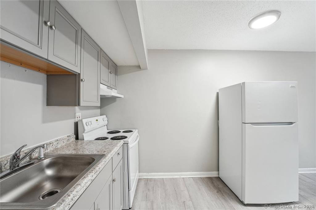 1150 Ogden St Extension, Unit 208 Bridgeport, CT 06610 - Photo 4 of 7 a kitchen with a sink a refrigerator and cabinets