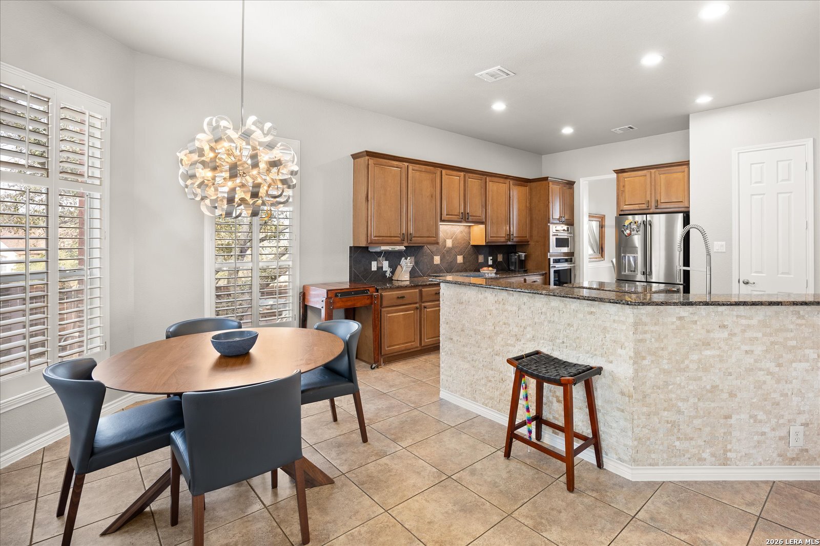 8718 Timberland Trail Fair Oaks Ranch, TX 78015 - Photo 16 of 50 a kitchen with a dining table chairs and large window