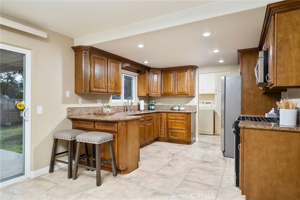 760 West Aster Street Upland, CA 91786 - Photo 6 of 40 a kitchen with granite countertop a stove top oven a sink dishwasher a dining table and chairs with wooden floor