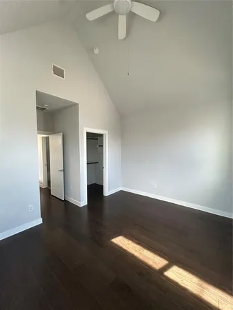an empty room with wooden floor fan and windows