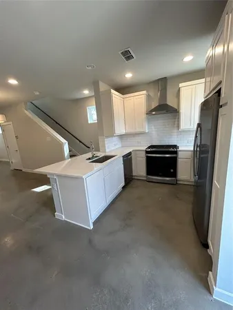 a large kitchen with stainless steel appliances a refrigerator a sink a stove and a sink