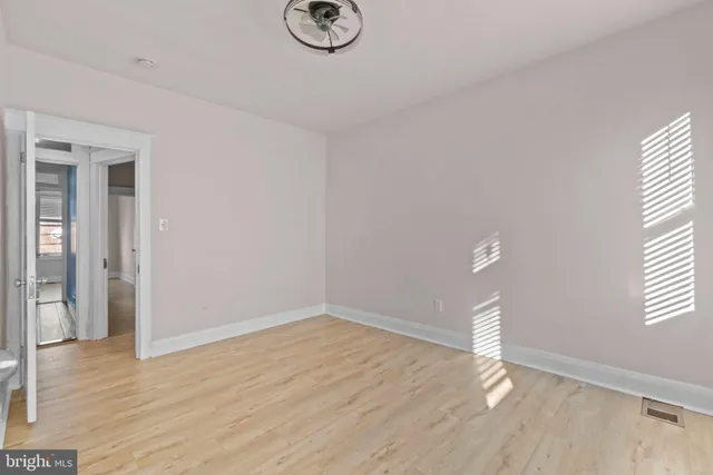 a view of empty room with wooden floor and window