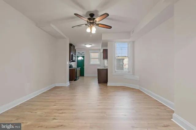 a view of an empty room with window and wooden floor