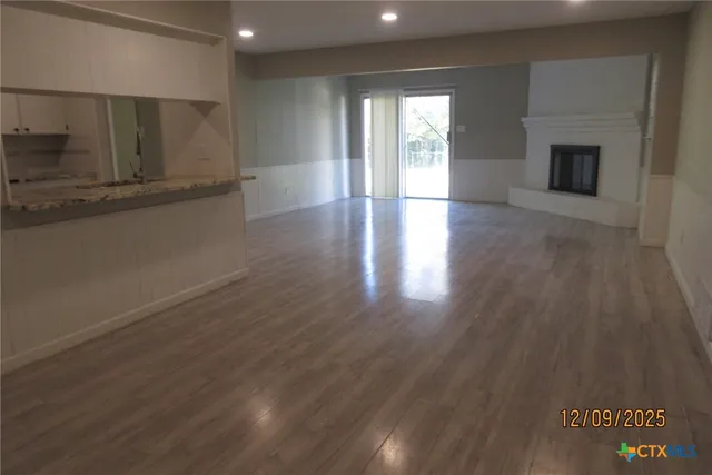 an empty room with wooden floor and fireplace