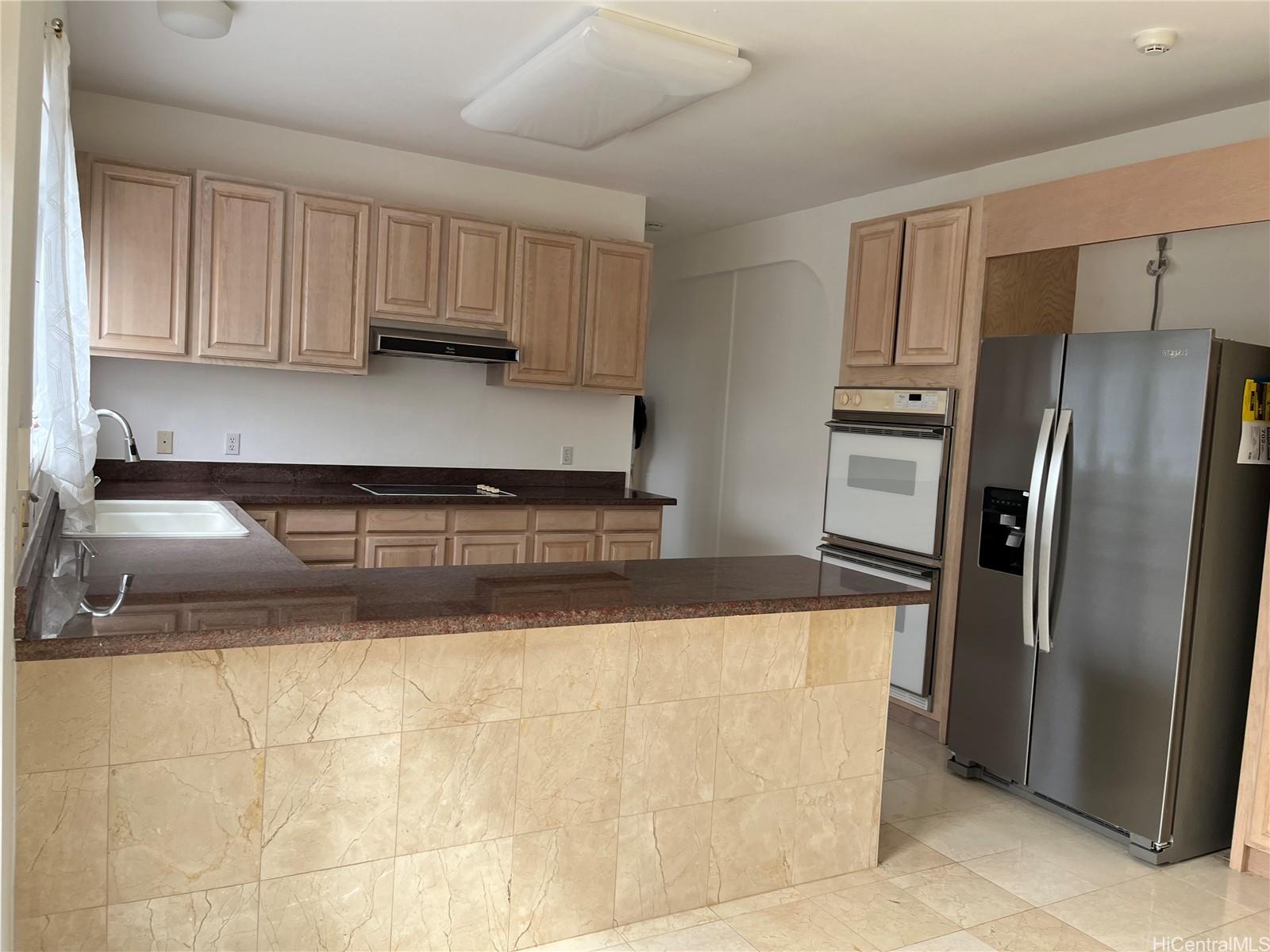 a kitchen with granite countertop a refrigerator sink and cabinets