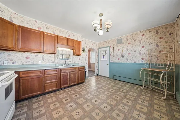 a kitchen with stainless steel appliances a sink a stove a refrigerator cabinets and dining table