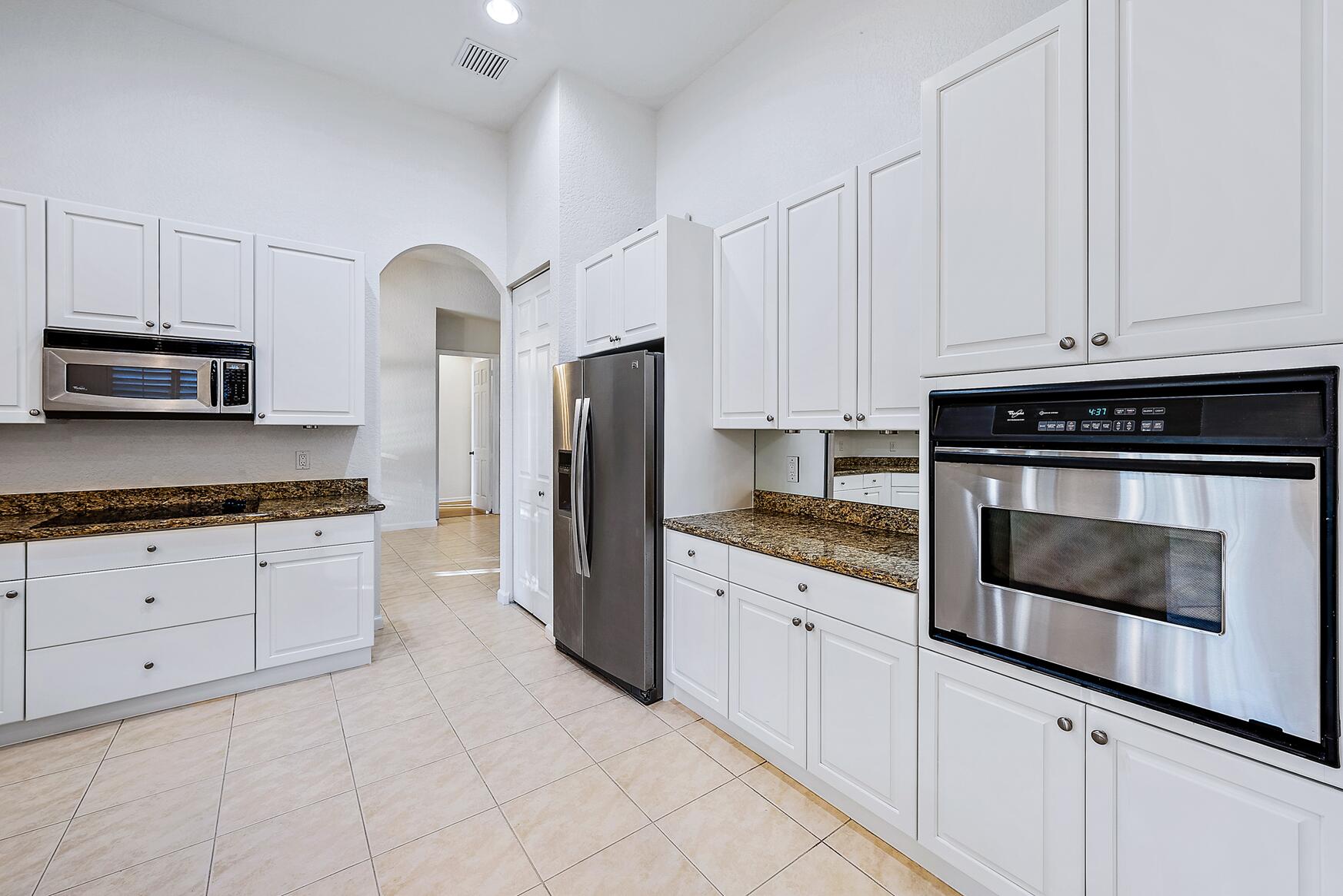 116 Via Rosina Jupiter, FL 33458 - Photo 8 of 33 a kitchen with granite countertop white cabinets and stainless steel appliances