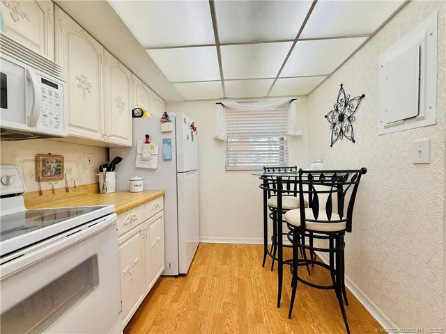 a kitchen with stainless steel appliances a white refrigerator a sink dishwasher and a stove with wooden floor