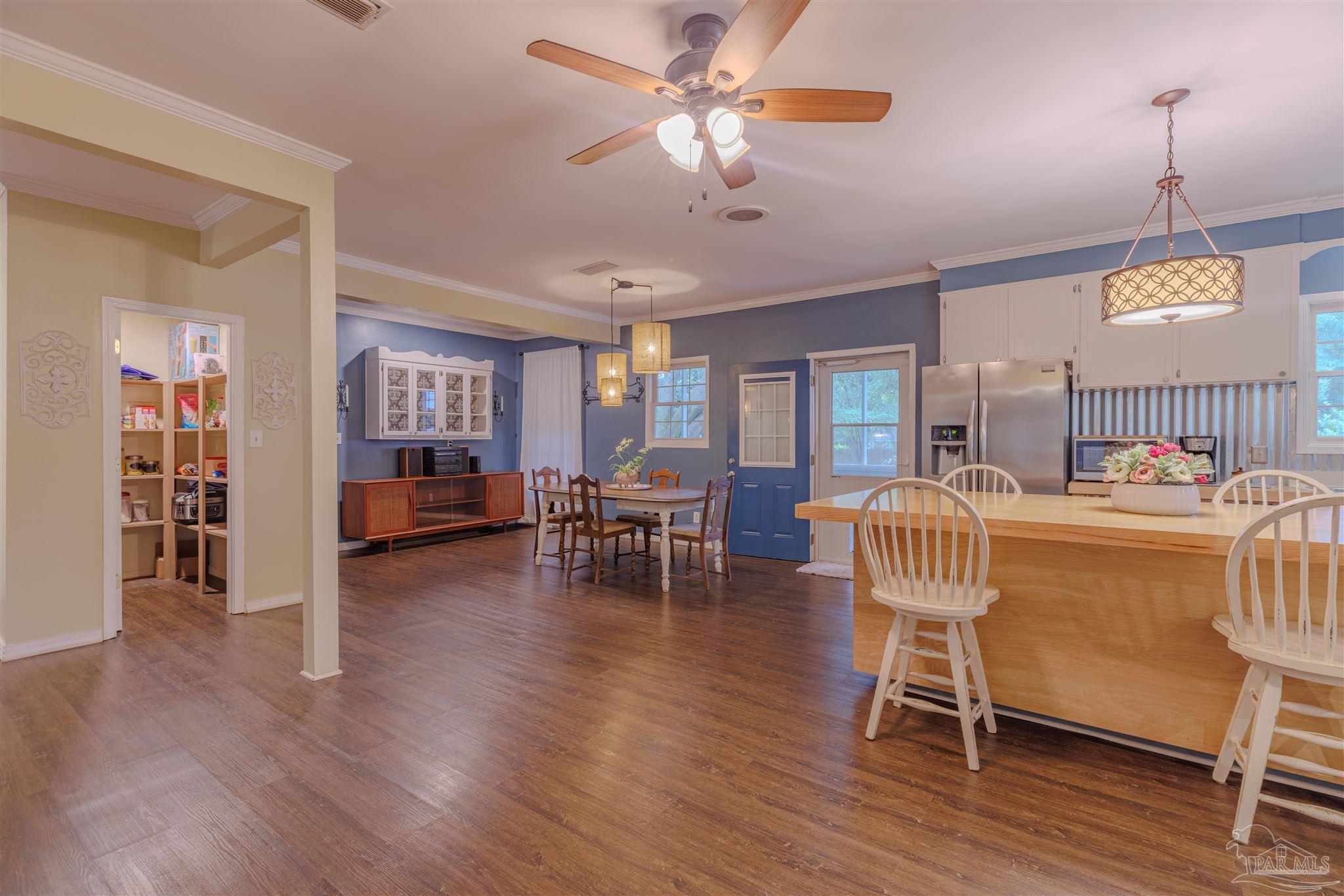 5049 Guernsey Road Pace, FL 32571 - Photo 22 of 61 a dining room with furniture a chandelier and wooden floor