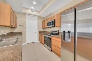 a kitchen with stainless steel appliances granite countertop a refrigerator a stove and a sink with wooden floor