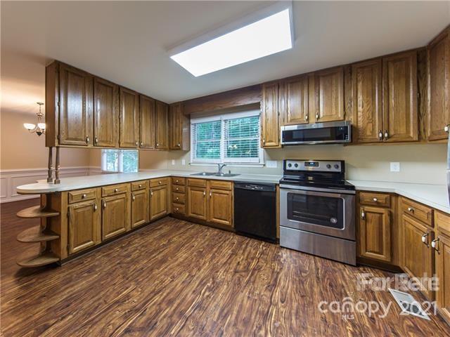 1347 Mistletoe Ridge Place Northwest Concord, NC 28027 - Photo 14 of 34 a kitchen with stainless steel appliances granite countertop wooden cabinets a stove top oven a sink and dishwasher with wooden floor