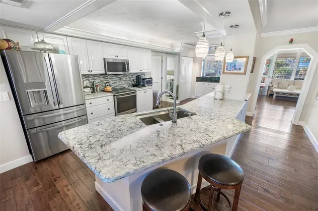 a kitchen with stainless steel appliances granite countertop a table chairs sink refrigerator and microwave